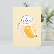 Load image into Gallery viewer, with a cute illustration of a dog in a banana peel on a light yellow background.Mini art print featuring a cute Bibo dog character peeking out of a peeled yellow banana, centered on a soft yellow background.