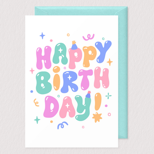A vibrant and playful birthday card featuring the words 'Happy Birthday!' written in large, colorful bubble letters. Each letter is uniquely styled in shades of pink, blue, green, and orange, with fun, festive accents like party hats, stars, and confetti scattered throughout the design. The card measures 4.25 inches by 5.5 inches and paired with a light teal envelope, creating a joyful and celebratory look.